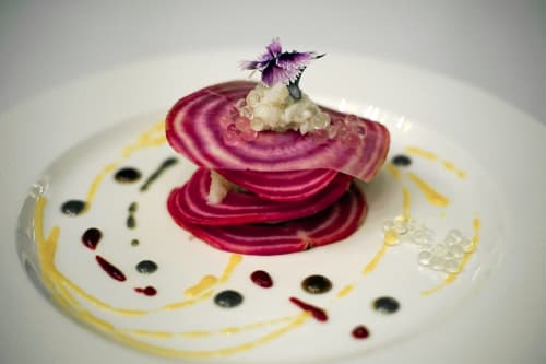 Elegant plated dessert with stacked beetroot crisps, caviar, and purple flower at Pavillon Des Millesimes, Lussac