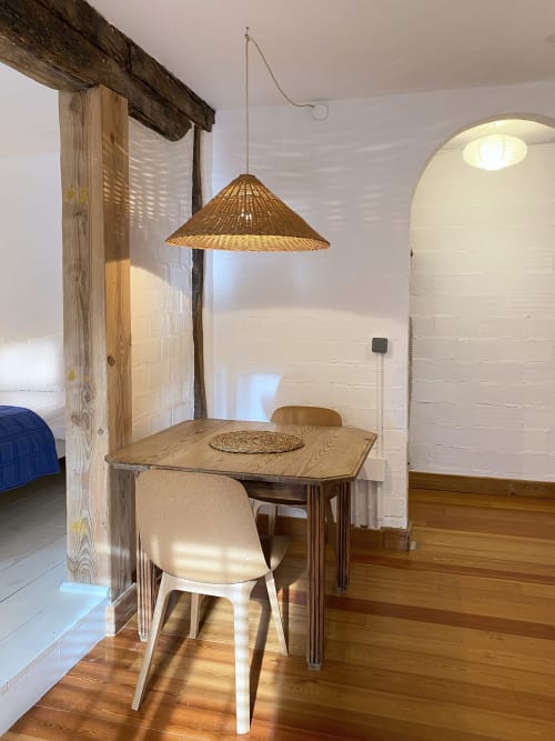 Comedor con mesa de madera, lámpara colgante tejida y silla blanca en Casa rural MAÑARINEGI Landa apartamentuak