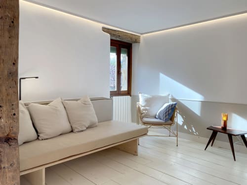 Habitación luminosa y minimalista en Casa rural MAÑARINEGI con sofá crema, pared de madera y luz natural desde el balcón