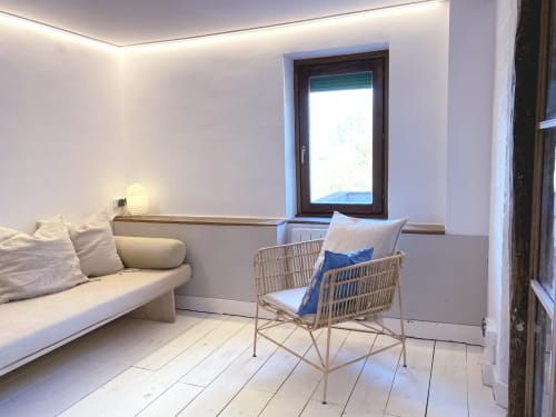 Luminosa zona de estar moderna con sofá blanco, silla tejida, vista al jardín e iluminación contemporánea en Casa