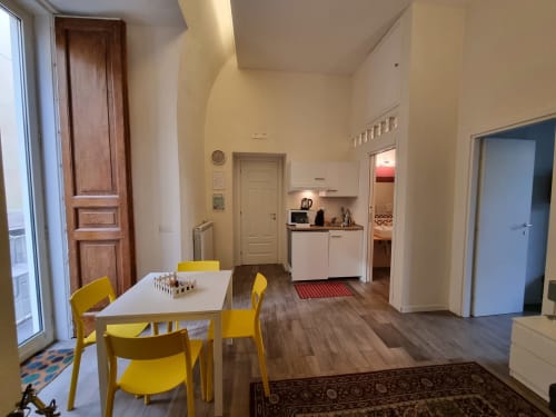 Spacious Suite de luxe family room at B&B Il Conservatorio Naples with yellow dining chairs, kitchenette, and city balcony