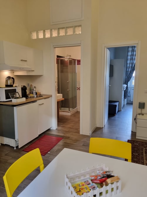 Modern kitchen-dining area in Naples luxury suite with yellow chairs, white cabinets, and bathroom access