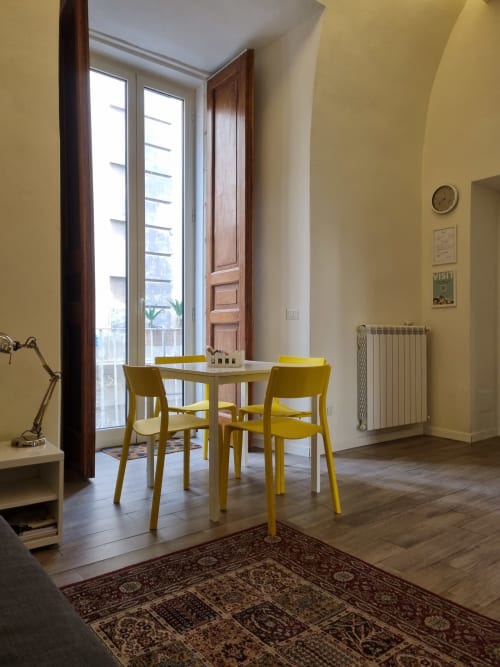 Modern suite at B&B Il Conservatorio Naples with yellow chairs, dining table, and city balcony view