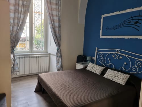 Elegant bedroom suite at B&B Il Conservatorio Naples with double bed, blue accent wall, city view window, and ornate