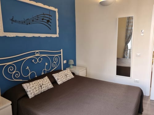 Elegant bedroom at B&B Il Conservatorio Naples with blue accent wall, ornate headboard, and musical note decor
