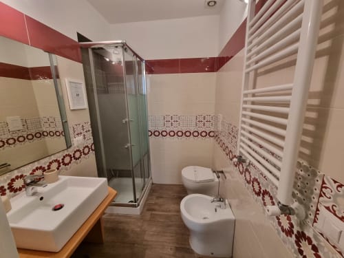 Modern bathroom in Suite de luxe at B&B Il Conservatorio Naples with red and white tiles, shower, bidet, sink, and heated