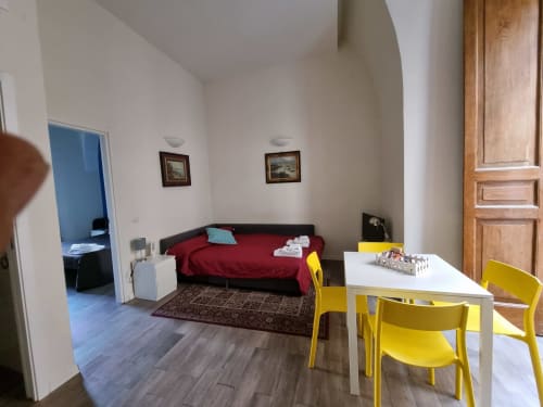 Suite de luxe family room at B&B Il Conservatorio in Naples with red sofa, yellow chairs, white desk, and wooden door