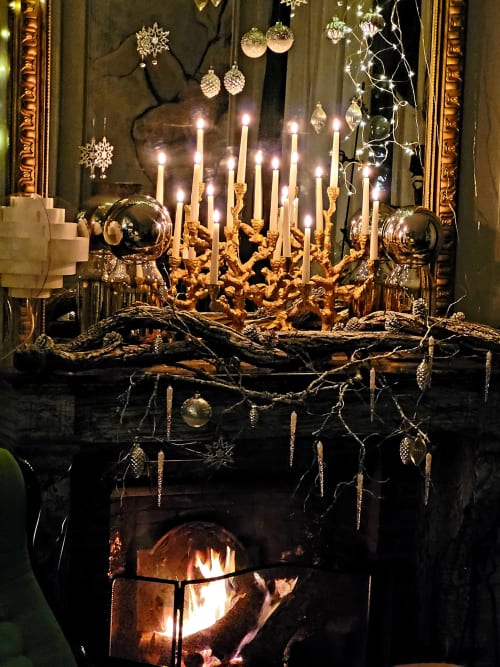 Cheminée luxueuse au Grand Duc avec candélabre doré ouvragé, lumières scintillantes et branches noires ornées d'or