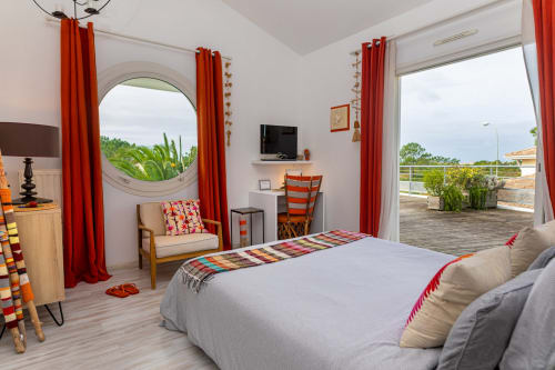 Chambre lumineuse à Côte Et Dune à Biscarrosse Plage avec rideaux rouges, fenêtre ronde et vue sur la terrasse