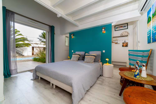 Chambre lumineuse à Côte Et Dune avec mur d'accent turquoise, lit gris, terrasse vue piscine et décoration côtière à Biscarrosse