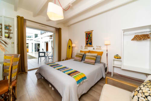 Chambre lumineuse à l'hôtel Côte Et Dune à Biscarrosse Plage avec lit, accès terrasse, touches décoratives jaunes et planche de surf