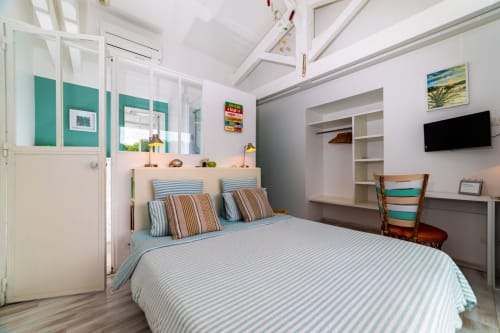 Chambre côtière lumineuse à Côte Et Dune avec accents turquoise, literie rayée et charme balnéaire à Biscarrosse Plage.