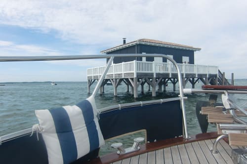 Boat view of Cote Et Dune stilt house with deck railing and turquoise water in Biscarrosse Plage, France