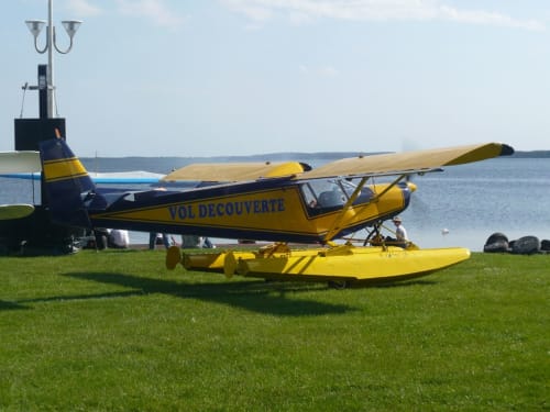 Hydravion jaune amarré sur l'herbe à la plage de Biscarrosse avec une eau et un ciel calmes