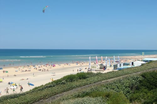 Plage de Biscarrosse avec son sable fin, baigneurs, kitesurfeur et structures colorées de plage