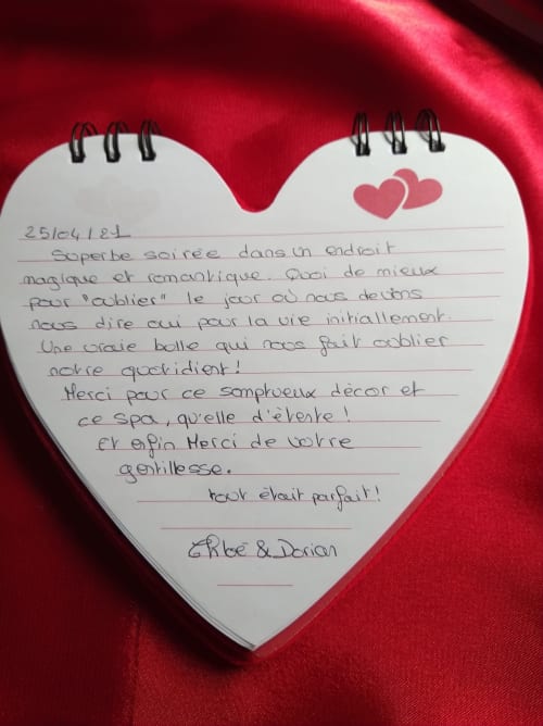 Bloc-notes en forme de cœur avec message manuscrit en français sur fond de velours rouge à L'Insolite Spa Privatif Toulouse