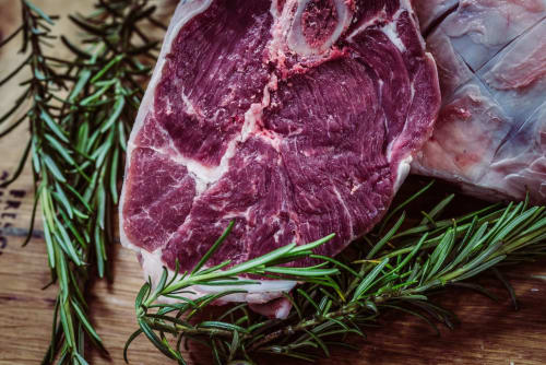 Bistecca di manzo cruda con rosmarino fresco su superficie in legno presso Casale di Poggioferro