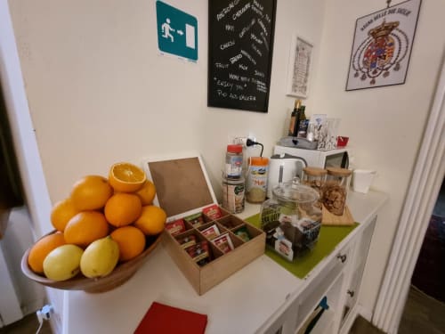 Mostrador de cocina del B&B Il Conservatorio Nápoles con naranjas frescas, cajas de té y artículos de despensa en estantes blancos