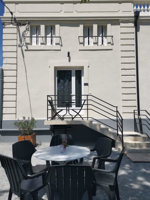Espace de détente en cour à la Résidence L'Hermitière avec table ronde, chaises noires et façade blanche moderne avec balcons