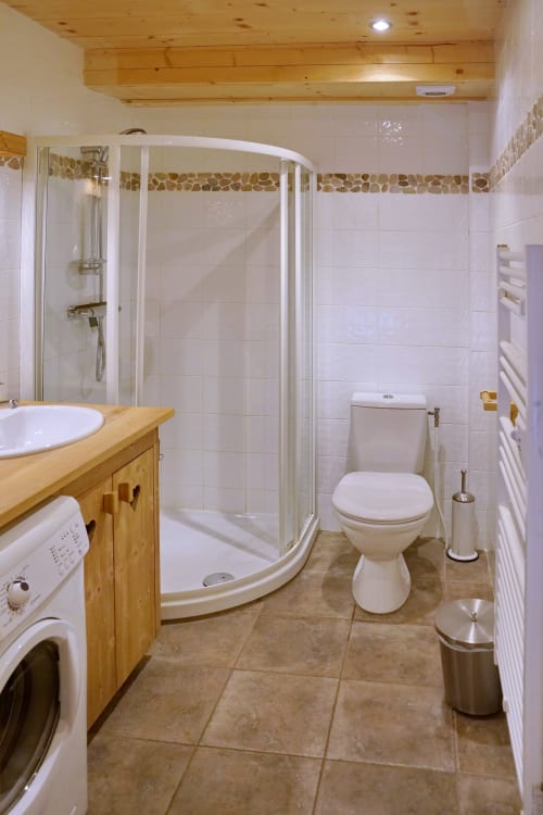 Salle de bain moderne avec douche, meuble vasque en bois et carrelage pierre au Chalet La Louvière, La Toussuire