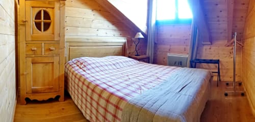 Chambre loft douillet au Chalet La Louvière avec literie à carreaux, vue montagne et intérieur rustique en sapin à La Toussuire