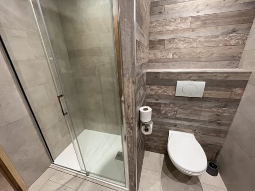 Salle de bains contemporaine avec douche à l'italienne, toilettes blanches et carrelage imitation bois à la villa Le Maquis Plage à Poggio-Mezzana
