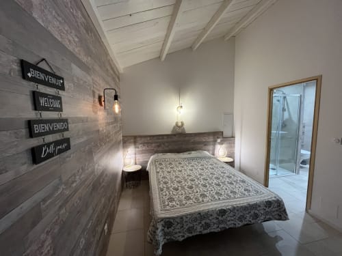 Chambre moderne de la villa Le Maquis Plage à Poggio-Mezzana avec panneaux de bienvenue, literie à motifs et entrée de douche vitrée