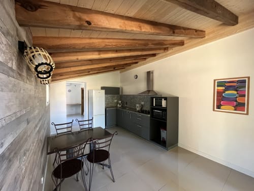 Cuisine moderne de la villa Le Maquis Plage avec poutres en bois, salle à manger et œuvres colorées
