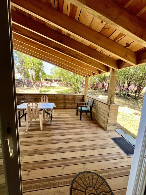 Terrasse en bois de la villa Le Maquis Plage avec table à manger, chaises et pergola ombragée surplombant le jardin à Poggio-Mezzana