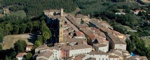 Vista aerea del villaggio di Pomarance con torre storica e tetti di terracotta circondata dal verde paesaggio toscano