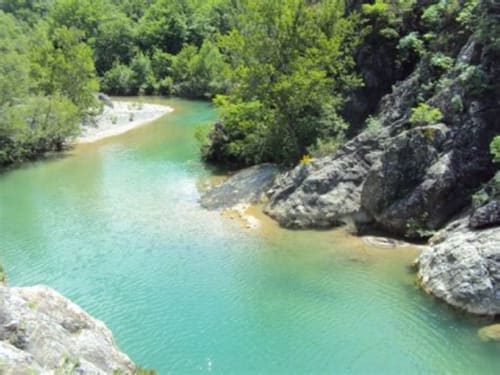 Fiume turchese con scogliere rocciose circondate da foresta verde vicino ad Agri-Bio Santa Palmira, Pomarance