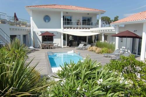 Terrasse piscine de l'hôtel Côte et Dune avec transats, parasols et villa blanche moderne à Biscarrosse Plage
