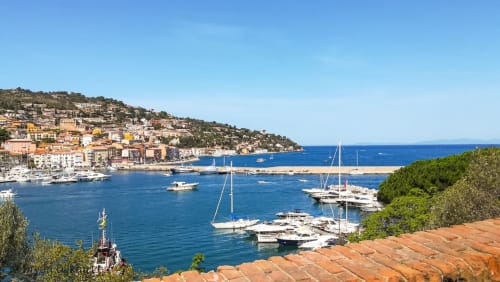 Pittoresco villaggio costiero con barche a vela nelle acque azzurre del Mediterraneo, Poggioferro, Italia