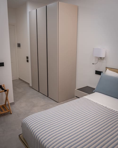 Modern bedroom at Museo19 apartment in Naples with striped bed, minimalist wardrobe, and wooden chair