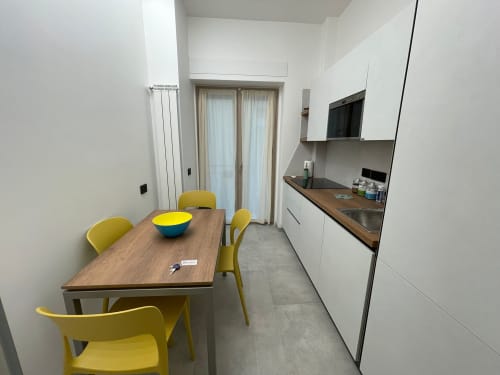 Modern kitchen-dining area at Museo19 apartment in Naples with yellow chairs, wooden table, and white cabinetry