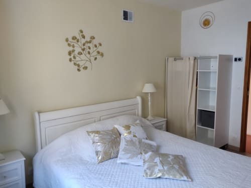 Chambre lumineuse de l'appartement MarjoRI au Lauzet-Ubaye avec lit blanc, coussins dorés et décoration vue montagne