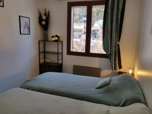 Chambre douillette de l'appartement Location MarjoRI à Le Lauzet-Ubaye, avec vue montagne par les fenêtres en bois