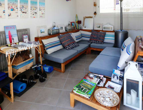 Salon bord de mer à l'hôtel Côte Et Dune de Biscarrosse avec mobilier en bois, coussins bleus et décoration côtière.