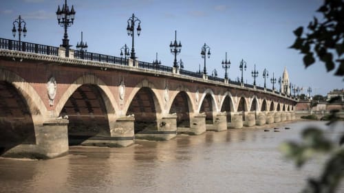 Pont en pierre historique à arches traversant la rivière, lanternes ornées et flèches, monument architectural bordelais près de Biscarrosse