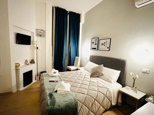Bright bedroom at AD Trastevere Guest House in Rome with queen bed, blue curtains, and modern amenities
