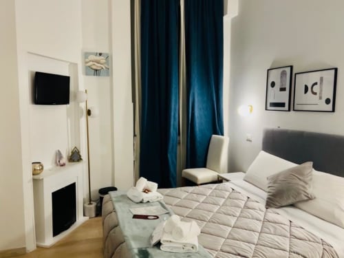 Modern bedroom at AD Trastevere Guest House in Rome with queen bed, blue curtains, wall-mounted TV, and contemporary artwork