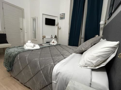 Modern guest room at AD Trastevere with gray quilted bedding, white pillows, and dark blue curtains