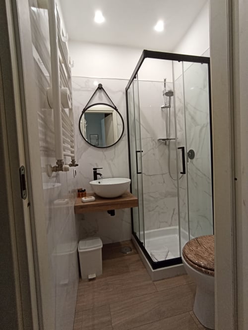 Bagno moderno presso AD Trastevere Guest House Roma con doccia in marmo, specchio rotondo e lavabo a ciotola