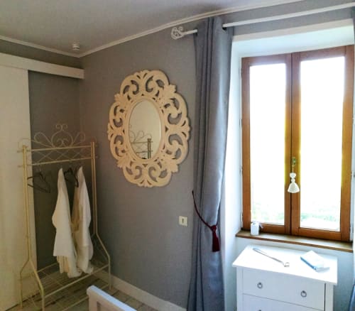 Elegant bedroom at Aux Prés Du Berry with ornate mirror, white dresser, garden view doors, and towel rack in Romance en Berry