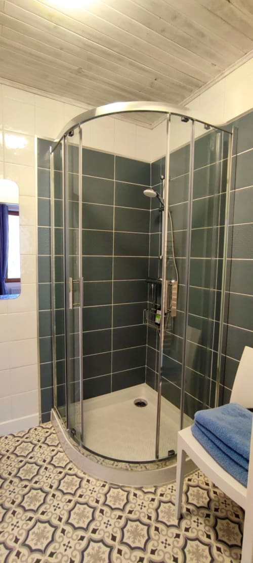 Modern shower enclosure with dark green tiled walls and curved glass doors in hotel room Douceur de l'Aube at Aux Prés Du
