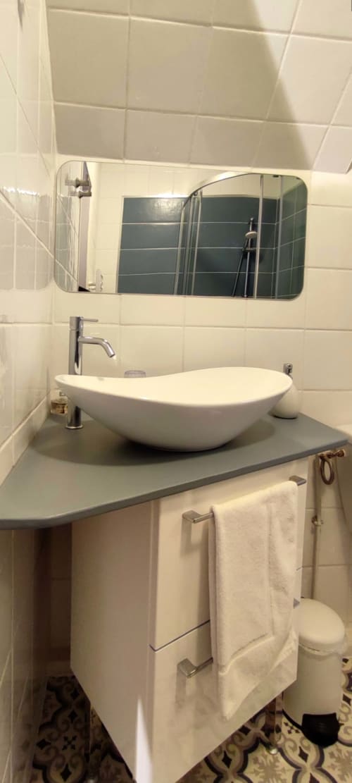 Modern bathroom at Aux Prés Du Berry with white vessel sink, gray countertop, and rectangular mirror in Chavin, France