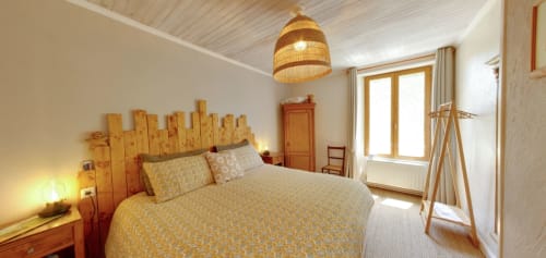 Cozy bedroom at Aux Prés Du Berry with wooden headboard, yellow bedding, woven pendant light, and terrace access in Chavin