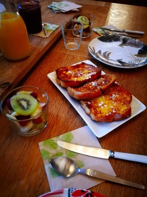 Breakfast spread at Aux Prés Du Berry B&B with French toast, fresh fruit, juice and beverages on wooden table