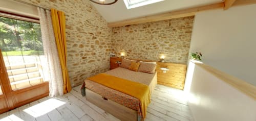 Bright bedroom at Aux Prés Du Berry B&B in Chavin, France, with stone walls, wooden floors, and ochre bedding