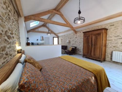 Rustic bedroom at Aux Prés Du Berry with exposed beams, stone walls, and modern amenities in Chavin